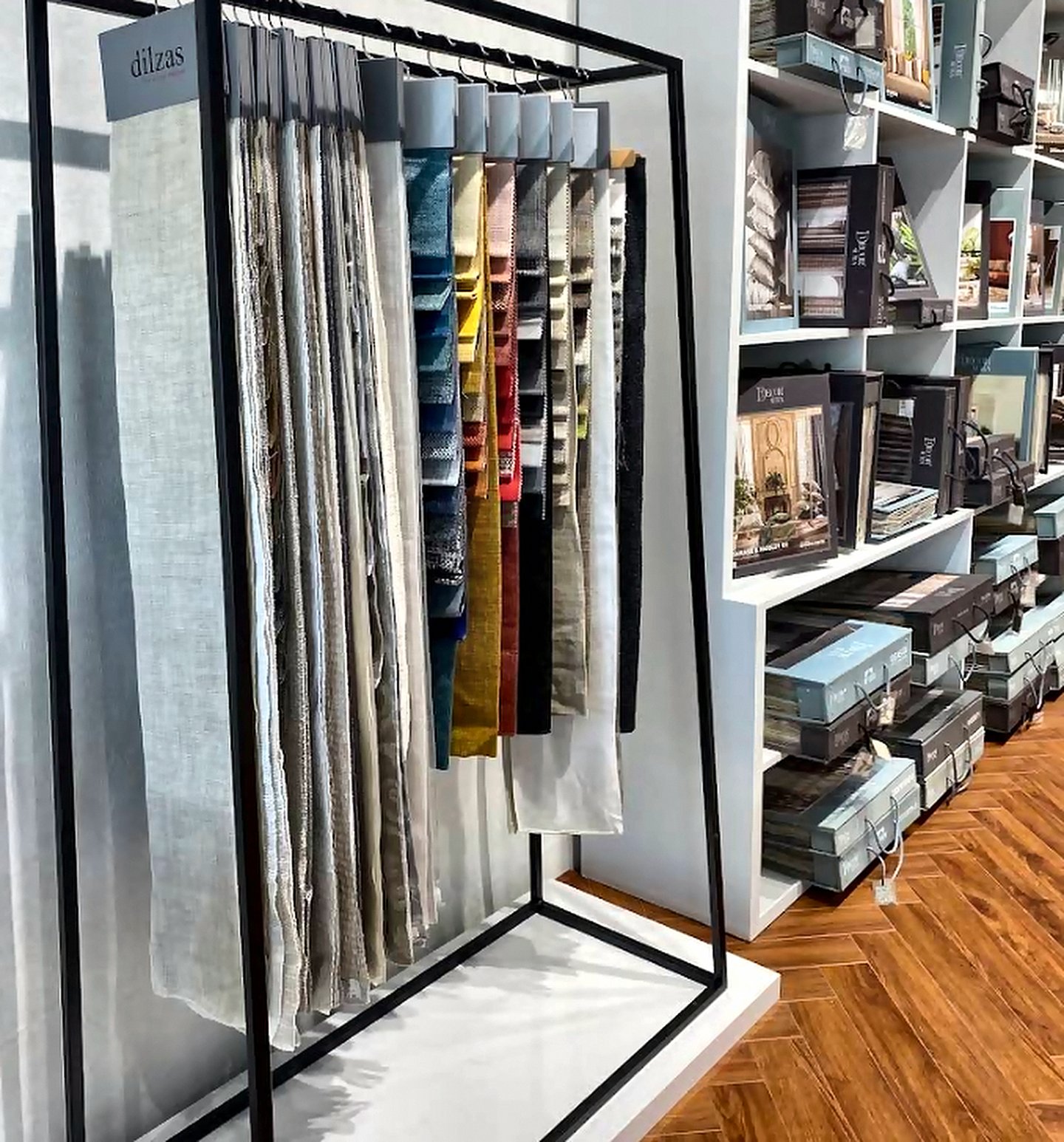 Curtain fabric swatches hanging on a black display rack inside the Goregaon West store
