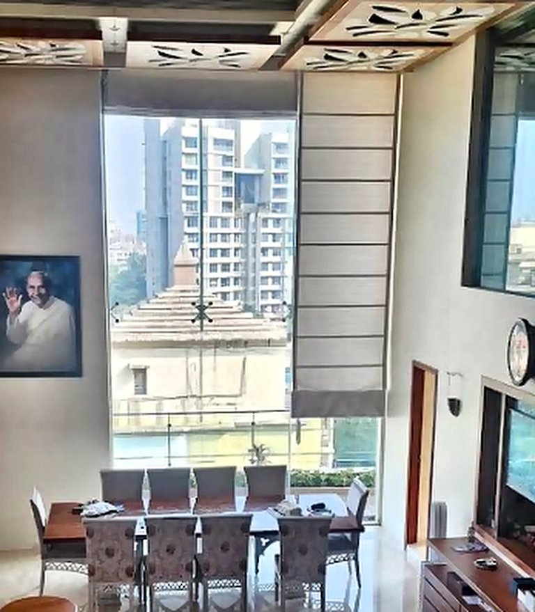 Roman blinds fitted to a tall living room window in Mumbai