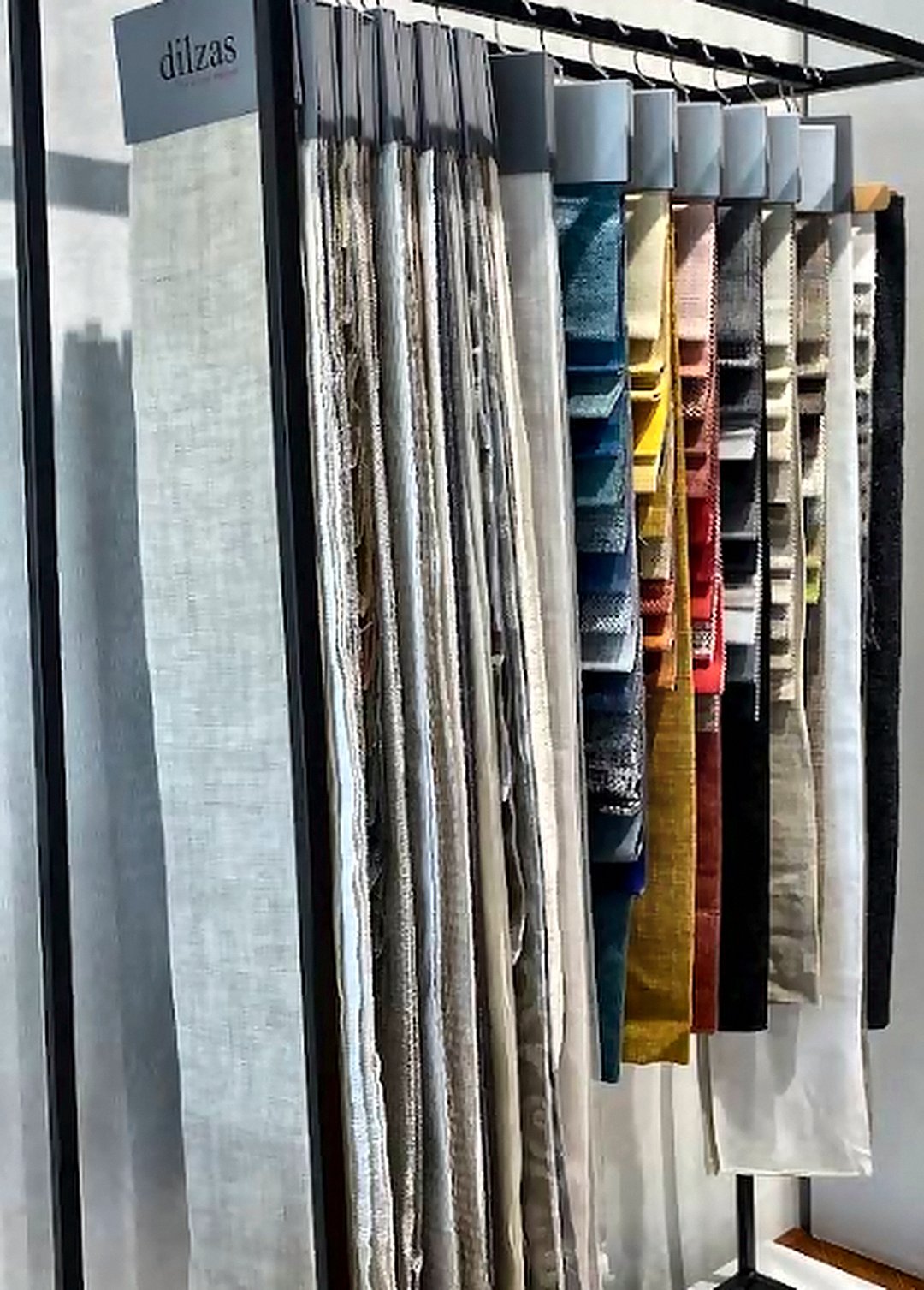 Sheer curtain fabric swatches hanging in the Opulence Decor showroom